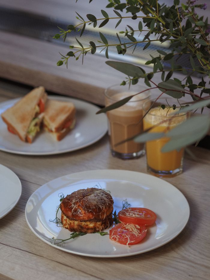 Appetizing brunch setup with sandwich, juice, and pastry on a wooden table.