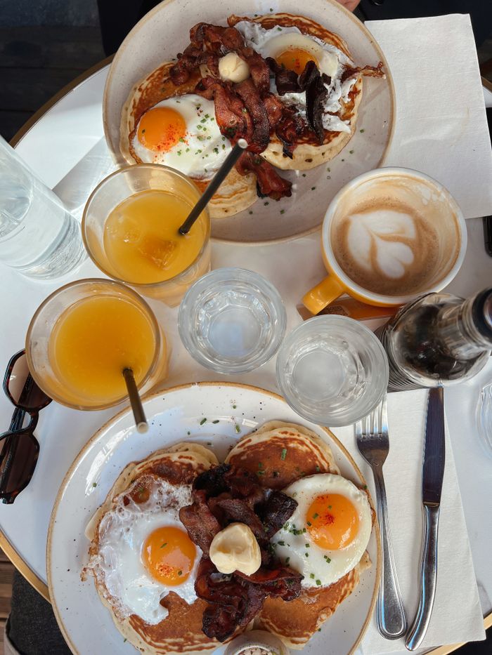 Aerial shot of breakfast table with bacon, eggs, and beverages.