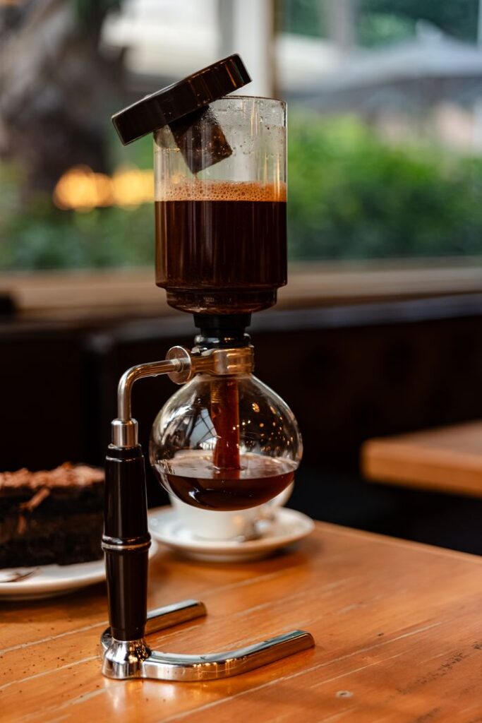 A siphon coffee maker beautifully brewing coffee on a wooden table inside a cozy cafe.