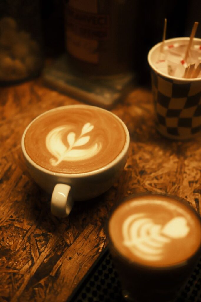 Warm-toned latte art featuring intricate designs in a cozy coffee shop setting.